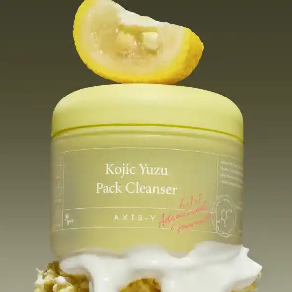 Conceptual stack of Axis-Y cleanser jar on white foam, under a yuzu slice, with olive-green background.