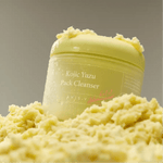 Axis-Y Kojic Yuzu cleanser jar resting on a fluffy, light-yellow soufflé texture in clear lighting.