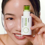 A smiling woman holding the Beplain Mung Bean Pore Tight-Up Serum bottle in front of her eye against a white background.