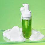 Celimax Noni Acne Bubble Cleanser bottle sitting in a pile of soft white foam on a green background.