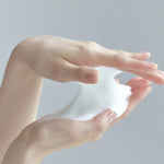 Rich white micro-bubbles from the Celimax Noni Cleanser being stretched between hands.