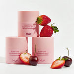 Three pink jars of House of Hur Purifying Cleansing Balm styled with fresh strawberries and cherries.