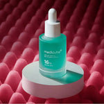 Medicube Azelaic Acid 16 serum bottle displayed on a white pedestal with a pink textured background.