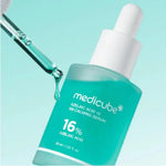 Close-up of a dropper dispensing a drop of turquoise Medicube Azelaic Acid serum.