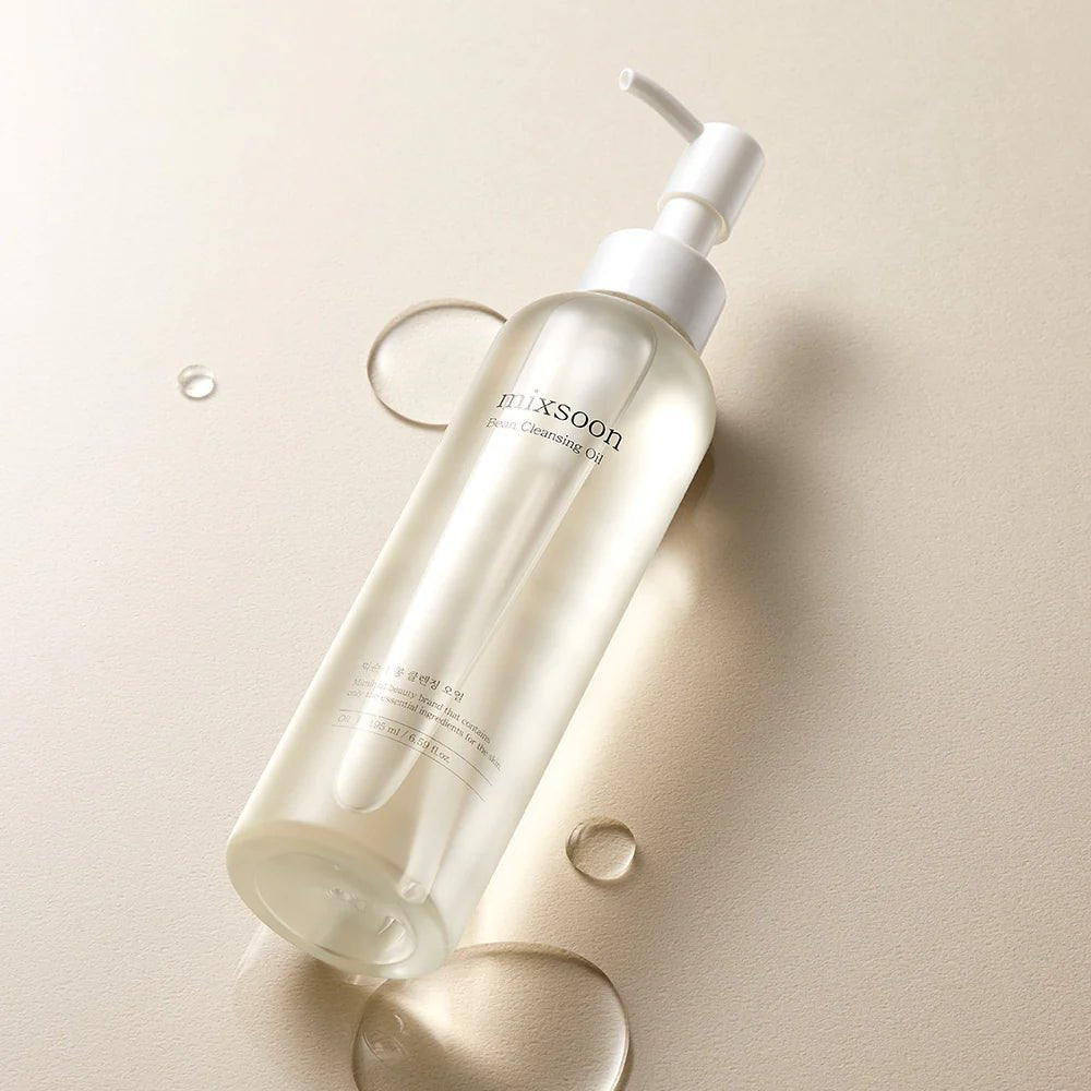 Mixsoon Bean Cleansing Oil bottle laying on a beige surface with clear oil droplets.