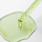 Dropper applying clear green Purito Azelaic Acid serum onto a smooth surface.