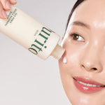 A smiling woman holding the Purito Oat PDRN Gentle Refining Toner bottle against her face.
