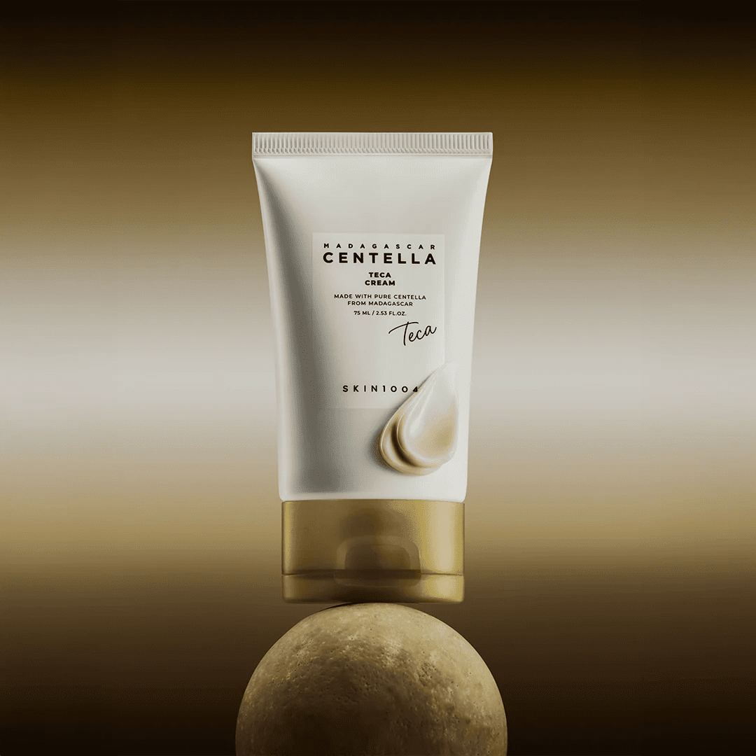 Skin1004 Madagascar Centella Teca Cream packaging balanced on a stone with a drop of white cream on the tube.