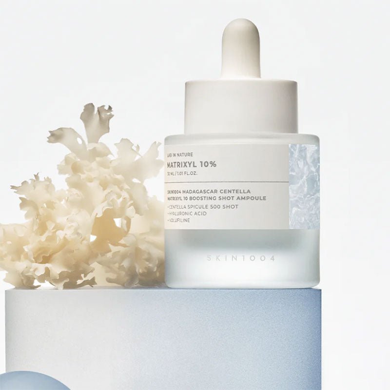 Skin1004 Matrixyl 10% Boosting Shot Ampoule bottle on a blue pedestal with white coral decor.
